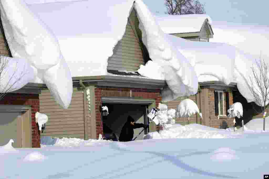 Snowdrifts create a beautiful setting as a man tries to dig out his driveway on Bowen Rd. in Lancaster, N.Y., Nov. 19, 2014. A lake-effect snow storm dumped over five feet of snow in areas across Western New York.