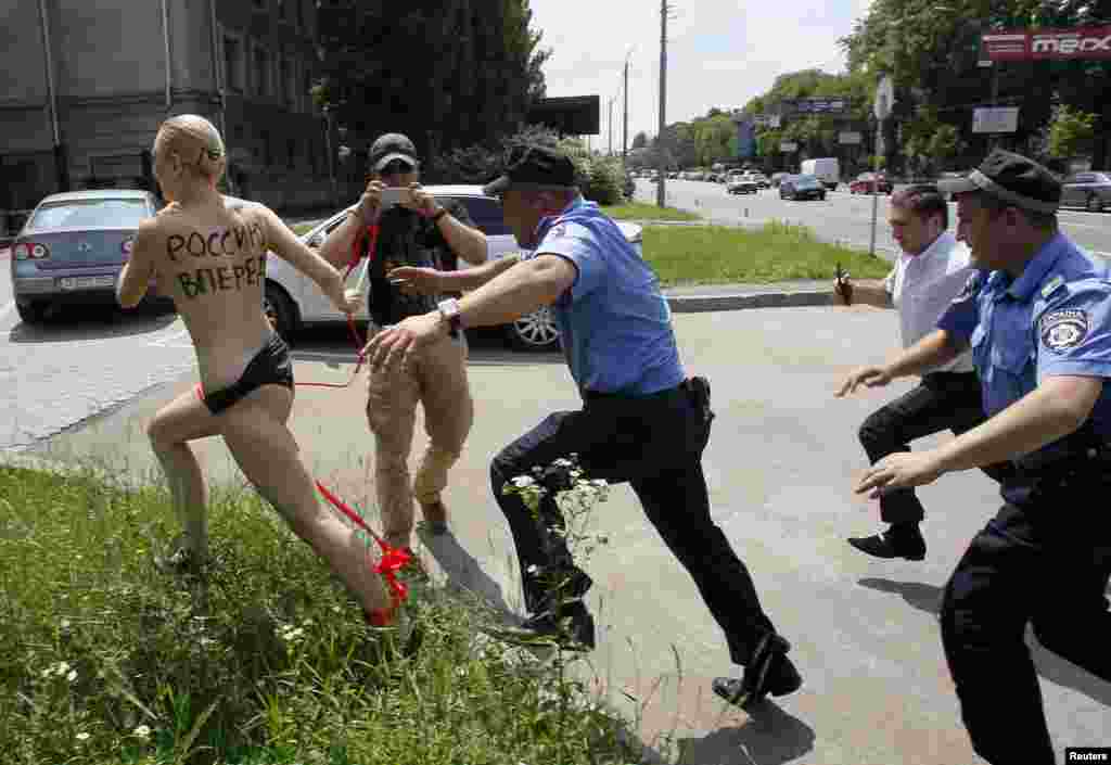Pejabat Kementerian Dalam Negeri Ukraina dan penjaga keamanan mengejar seorang aktivis dari kelompok hak-hak perempuan FEMEN, ketika melakukan demonstrasi di Kedutaan Besar Rusia&nbsp; menanggapi pengumuman Presiden Rusia Vladimir Putin yang menyatakan perceraian dengan istrinya Lyudmila, di Kiev. Kata-kata yang tertulis di punggung perempuan itu berbunyi &quot;Dorong Rusia untuk Maju&quot; 