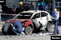 Investigators inspect a damaged car at the site where journalist Pavel Sheremet was killed by a car bomb in central Kiev, Ukraine, July 20, 2016.