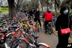 Residents riding bicycles from bike-sharing company Ofo try to pedal through a sidewalk crowded with bicycles near a bus stand in Beijing, China, March 23, 2017.