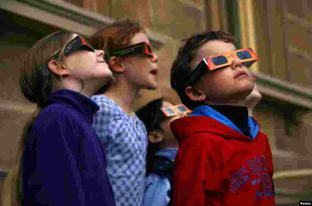 Children wear protective glasses as they try to see a partial solar eclipse from Sydney's Observatory Hill, Australia.