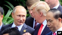 Le président russe Vladimir Poutine et le président américain Donald Trump discutent lors de la photo de famille au sommet de la Coopération économique Asie-Pacifique (APEC) à Danang, Vietnam, 11 novembre 2017. 