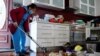 Xuan Nguyen cleans up inside a damaged home following severe flooding in the Maribyrnong suburb of Melbourne, Australia, Oct. 17, 2022. 