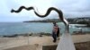 Visitors look at the sculpture 'Flooded Weir' by Vlase Nikoleski on display between Bondi and Tamarama beach as part of the Sculpture by the Sea exhibition in Sydney on Oct.21, 2022. 