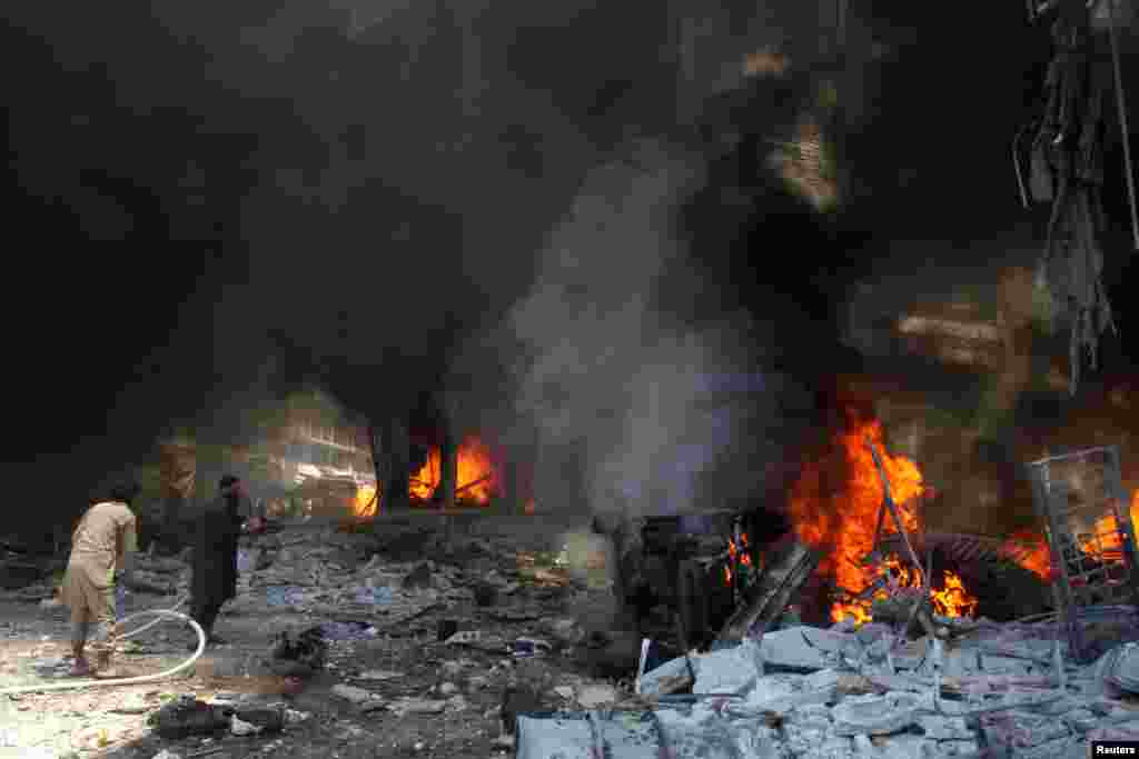 Men try to put out a fire at a market hit by air strikes in Idlib city, Syria June 12, 2016.