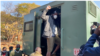 Le journaliste Hopewell Chin'ono lève le poing devant ses collègues, sa famille et ses amis alors qu'il monte dans un véhicule de prison, le 23 juillet 2020, devant le tribunal de Harare. (Photo: Columbus Mavhunga/VOA)