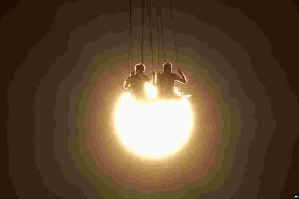 People enjoy a swing ride as the sun sets at an amusement park, in Athens, Greece, June 29, 2016.