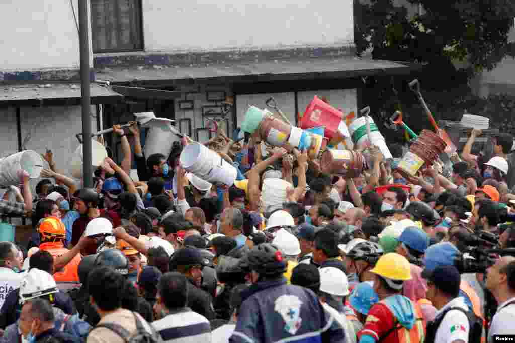 People pass buckets and shovels to remove the rubble of a collapsed building after an earthquake hit Mexico City, Sept. 19, 2017.