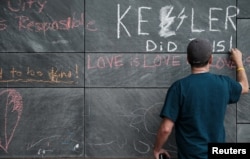 FILE - Russ Naranjo of Charlottesville writes a message about "Unite the Right" rally organizer Jason Kessler and the rally on the city's "Free Speech Wall" along the downtown mall in Charlottesville, Virginia, Aug. 14, 2017.
