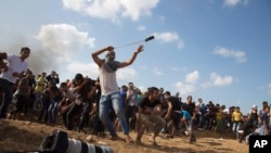Seorang warga Palestina tengah berupaya melempar batu ke arah tentara Israel dalam kekerasan di perbatasan sebelah timur kota Gaza (9/10).