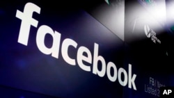 FILE- The logo for Facebook appears on screens at the Nasdaq MarketSite in New York's Times Square, In this March 29, 2018. A report says Facebook and the FTC are negotiating a "multibillion dollar" fine for the social network's privacy lapses.