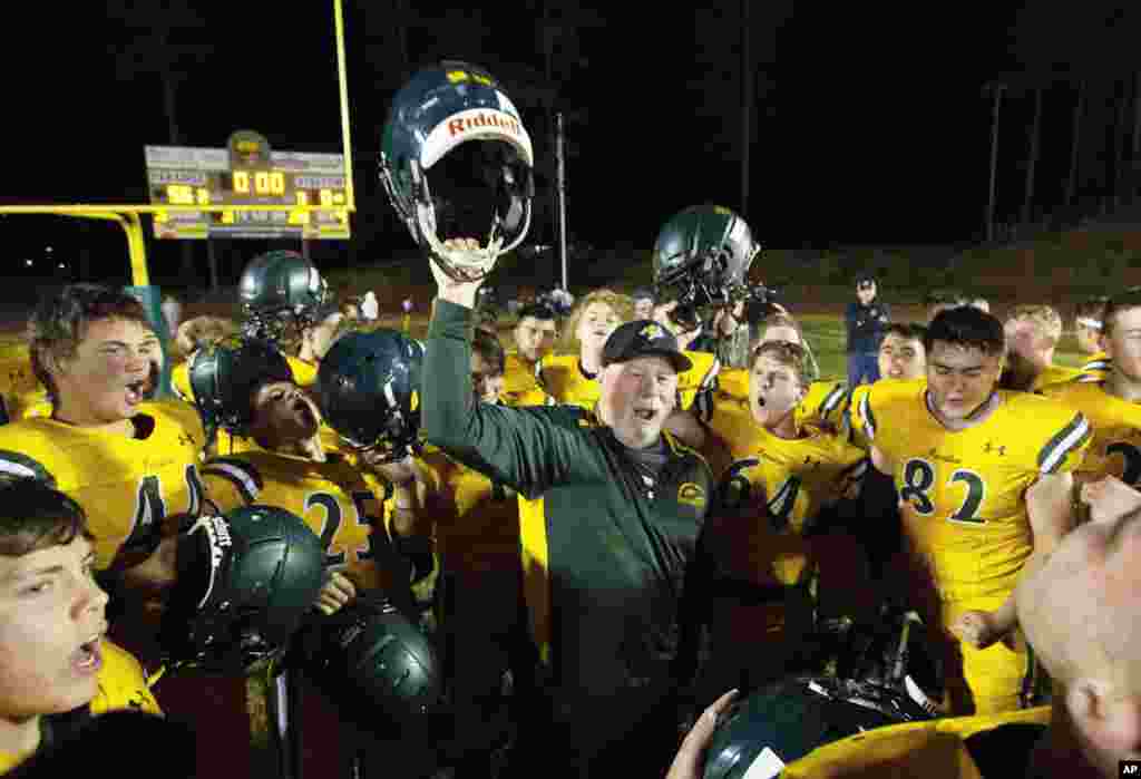 Paradise High School head football coach Rick Prinz, center, celebrates with his team after defeating Live Oak High School, 56-0, in their Northern California Division III playoff game in Paradise, Calif., Nov. 15, 2019. 