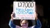 Demonstrator Gina Dusterhoft holds up a sign as she walks to join others standing across the street from the federal courthouse in Houston, Texas, Nov. 2, 2020, before a hearing involving drive-thru ballots cast in Harris County.