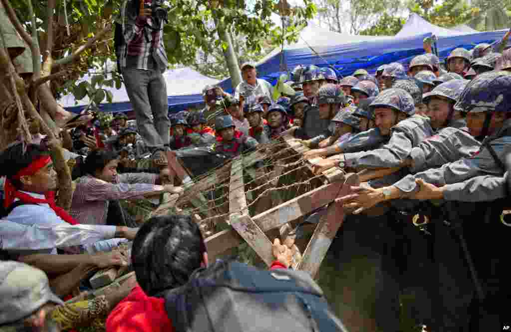 Para demonstran mahasiswa berhadapan dengan polisi huru-hara untuk mendorong barikade yang dipasang polisi dalam sebuah demonstrasi di Letpadan, Myanmar (10/3). (AP/Gemunu Amarasinghe)