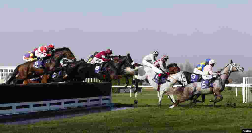 Horses and riders clear the water jump during the RSA Steeple Chase at the Cheltenham Festival horse racing meet in Gloucestershire, western England.