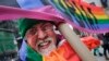 L'artiste Gilbert Baker, créateur du drapeau arc-en-ciel, porte une pancarte " Boycottons l'homophobie" lors de la parade pour la Saint Patrick à New York, le 17 mars 2014 