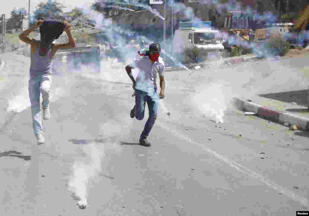 Para pengunjuk rasa Palestina melarikan diri&nbsp; dari gas air mata yang disemprotkan oleh pasukan Israel dalam&nbsp; bentrokan dekat penjara Israel Ofer di dekat kota Ramallah, Tepi Barat.&nbsp; &nbsp;