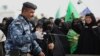 An Iraqi policeman uses a bomb detector to search Shi'ite pilgrims heading to the Shi'ite holy city of Karbala, 80 kilometers (50 miles) south of Baghdad, Iraq, Dec. 10, 2014. 