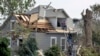 Workers pause while working on house damaged by a tornado in Pilger, Nebraska, June 18, 2014. 