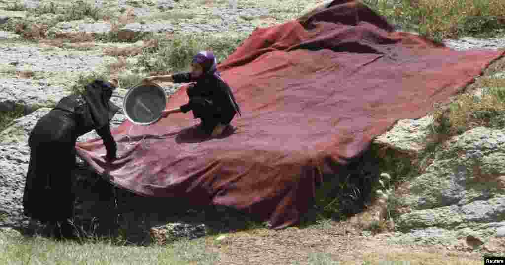 A girl helps her mother wash a large piece of fabric, outside Sana'a, Yemen.