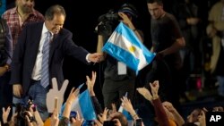 FILE - Ruling party presidential candidate Daniel Scioli, a no-show at the debate, holds an Argentine flag as he acknowledges supporters after primary elections in Buenos Aires, Argentina, Aug. 10, 2015.