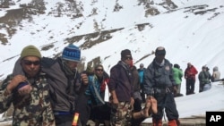 Nepalese army, rescue team members carry avalanche victims to safety at Thorong La pass area, Oct. 17, 2014.