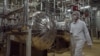 FILE - Wearing protective clothes, an Iranian security person walks at a part of the Uranium Conversion Facility just outside the city of Isfahan, Iran. Iran has removed the sensitive core of its Arak nuclear reactor and U.N. inspectors will visit the site on Thursday to verify.
