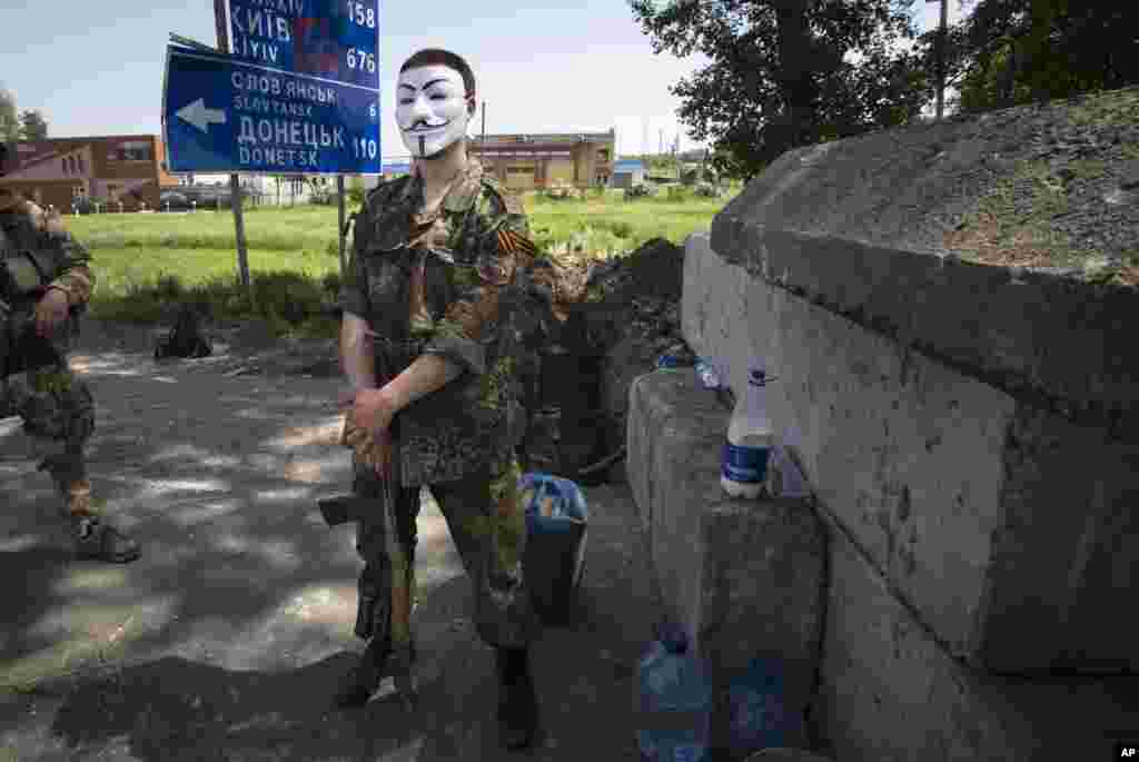 Seorang militan pro-Rusia yang bertopeng berdiri di belakang barikade di sebuah pos pemeriksaan yang menghalangi jalan layang di luar kota Kharkiv, Ukraina timur (17/5).&nbsp;(AP/Alexander Zemlianichenko)