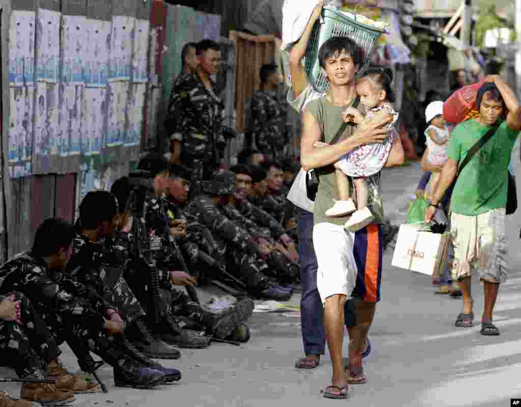 Residents who abandoned their homes carry their belongings during a standoff in Zamboanga, Philippines, Sept. 10, 2013.