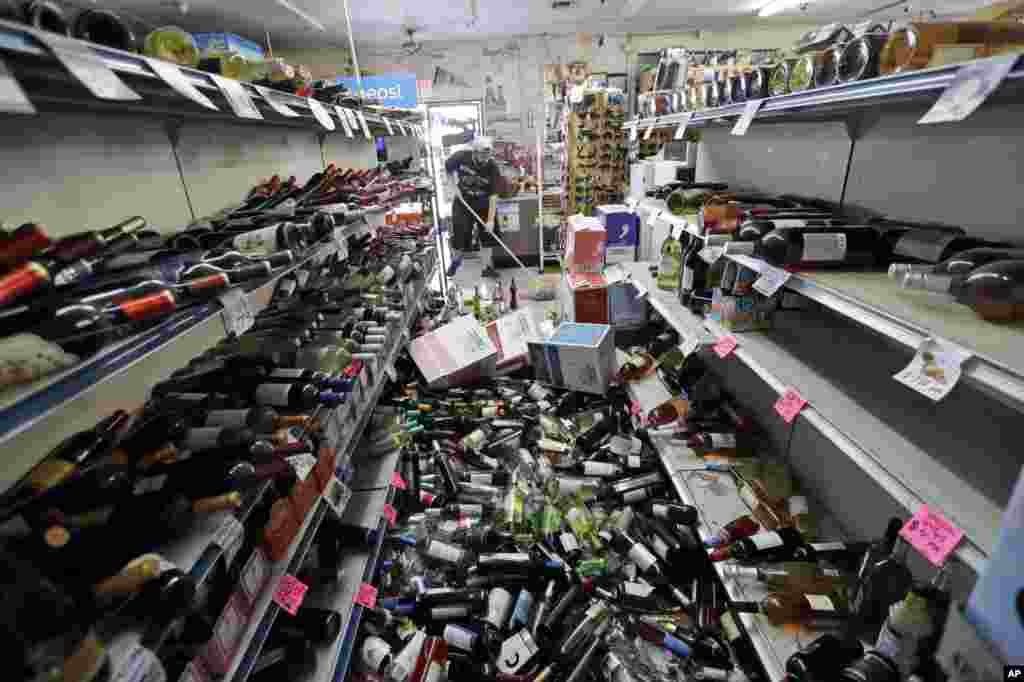 Bottles of wine are strewn in the middle of an aisle as Victor Abdullatif, background center, mops inside of the Eastridge Market, his family&#39;s store, July 6, 2019, in Ridgecrest, California. Crews in Southern California assessed damage to cracked and burned buildings, broken roads, leaking water and gas lines and other infrastructure after the largest earthquake the region has seen in nearly 20 years jolted an area from Sacramento to Las Vegas to Mexico.