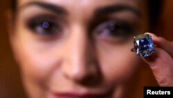 A model holds a 12.03-carat, cushion-shaped blue diamond mounted on a ring at Sotheby's auction house in Geneva, Nov. 4, 2015.