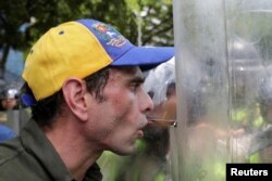 FILE - Venezuelan opposition leader Henrique Capriles talks to riot police at a June 7 rally in Caracas to demand a referendum.
