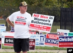 FILE - A man holds a sign that reads "No men in women's bathrooms" while protesting in Houston, Oct. 21, 2015.