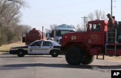 FILE - Firefighters move past a road block near Hutchinson, Kansas, March 7, 2017.