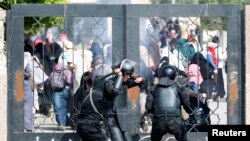 Polisi Mesir berusaha mendobrak pintu masuk di Universitas Al-Azhar dalam bentrokan dengan pendukung Ikhwanul Muslimin (19/3).