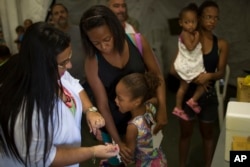 Tais da Silva Almeida comforts her 5-year-old daughter as a health worker prepares to inject her with a yellow fever vaccine in a field hospital in Casimiro de Abreu, Brazil, March 17, 2017.