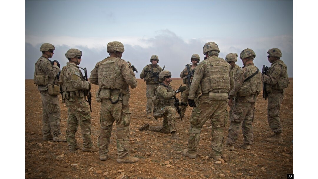 FILE - Photo released by the U.S. Army shows U.S. soldiers gathering for a brief during a combined joint patrol rehearsal in Manbij, Syria, Nov. 7, 2018.