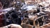 Polisi forensik berjalan melewati mobil-mobil yang hancur di dekat lokasi ledakan bom pada 12 Oktober 2002 di Kuta, Bali, 18 Oktober 2002. (Foto: Reuters)