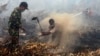 Warga desa dan anggota TNI berusaha memadamkan kebakaran hutan dan lahan di Rimbo Panjang, provinsi Riau (6/9). Presiden Jokowi memerintahkan tindakan hukum yang tegas terhadap pihak yang bertanggung jawab atas kebakaran hutan.