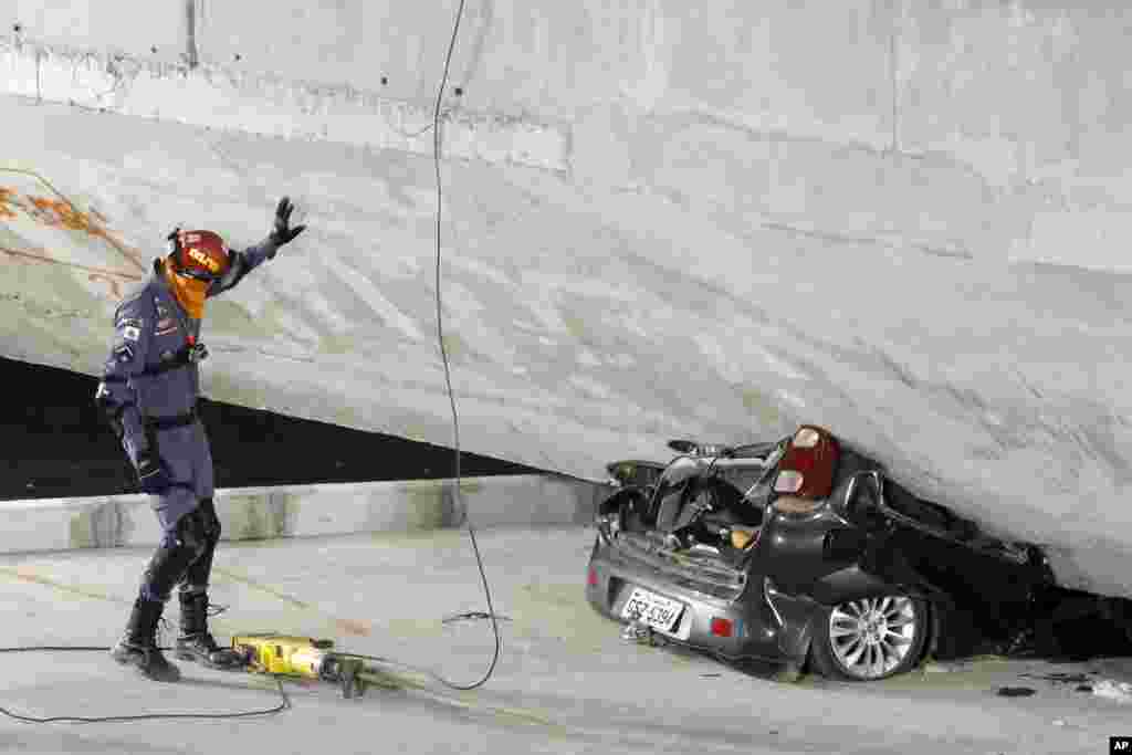 Polisi mengamati sebuah mobil yang ringsek di bawah jembatan yang ambruk di Belo Horizonte, Brazil, 3 Juli 2014. &nbsp;