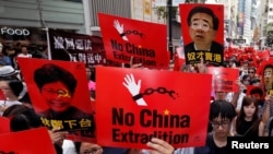 FILE - Demonstrators hold signs protesting an extradition bill during a rally in Hong Kong, June 9, 2019.