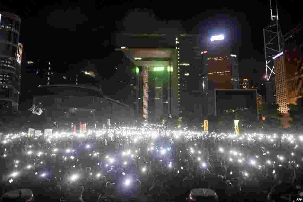 Para demonstran melambaikan ponsel dan alat elektronik lain saat melakukan protes pro-demokrasi di kompleks pemerintahan Hong Kong (31/8). (AFP/Alex Ogle)