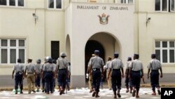 Zimbabwean police officers clear pamphlets left after a demonstration protesting delays in the drafting of a new constitution outside the parliament in Harare, Tuesday, Sept. 11, 2012. 