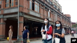 People wearing face masks to help curb the spread of the coronavirus walk on a street in Taipei, Taiwan, Monday, Oct. 19, 2020. (AP Photo/Chiang Ying-ying)