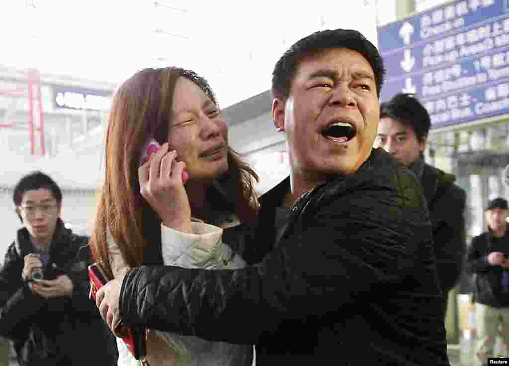 Kerabat penumpang Malaysia Airlines penerbangan MH370 menangis sambil menelepon di Bandar Udara Internasional Beijing.