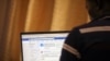 FILE - A man opens the Facebook page on his computer to fact check coronavirus disease (COVID-19) information, in Abuja, Nigeria, March 19, 2020