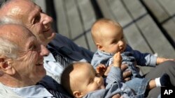 In this Saturday, June 18, 2005 file photo, identical twins Alf, left, and Sven Fehnhanhn, left background, 79, from Kassel, Germany, pose along with seven-month-old Luis Carl, right, und Albert Frank Millgramm, right background, during a twins' meeting i