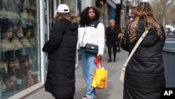 Women walk past a hairdressing salon on March 28, 2024, in Paris. Lawmakers in France's lower house of parliament approved a bill that would ban discrimination over the texture, length, color or style of someone's hair.