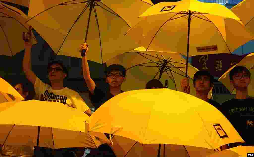 Joshua Wong (tengah, kiri) dan Alex Chow bergabung bersama para pemimpin gerakan payung "Umbrella Movement" dalam mengembangkan payung mereka dalam demonstrasi yang memperingati satu bulan sejak dimulainya protes-protes di Hong Kong. (VOA/Ivan Broadhead).