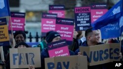 Demonstrators hold up placards in support of a strike by nurses outside St Thomas' Hospital in London, Dec. 20, 2022.